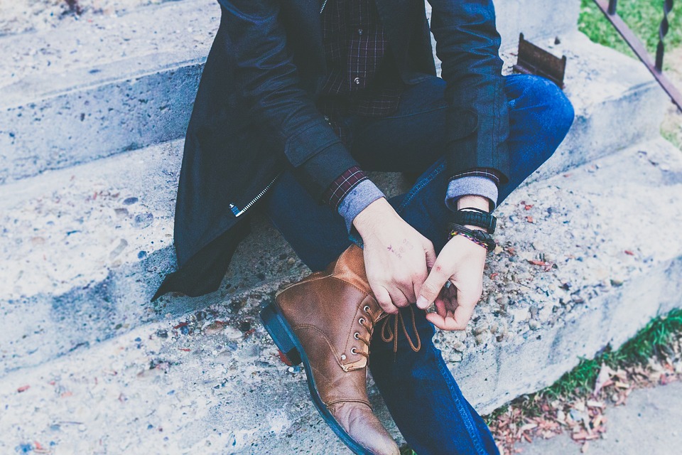 Jeune homme habillé avec une tenue chic composée d'un jean, d'une chemise d'une veste et de bottines en cuir