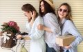 3 jeunes femmes posant sur un v&eacute;lo avec des fleurs et un colis